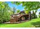 A lush green backyard surrounds a brick home with a large deck and stairs, shaded by mature trees at 1860 Red Fox E Ct, Martinsville, IN 46151