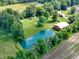 Stunning aerial view of a property featuring a pond, red barn, grassy area, trees, and a home at 19702 Centennial Rd, Sheridan, IN 46069