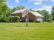 Spacious backyard with green lawn and farmhouse featuring a windmill, offering a peaceful and scenic view at 19702 Centennial Rd, Sheridan, IN 46069