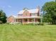 Charming brick home with a metal roof and a welcoming front porch surrounded by lush, well-manicured lawn at 19702 Centennial Rd, Sheridan, IN 46069