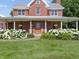 Attractive brick home featuring a metal roof, covered front porch, and professionally landscaped flower beds at 19702 Centennial Rd, Sheridan, IN 46069