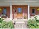 Inviting front porch with brick facade, wooden door, and decorative plants creates a warm and welcoming entrance at 19702 Centennial Rd, Sheridan, IN 46069
