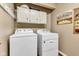 Functional laundry room with washer, dryer, and overhead cabinets for storage at 206 Cranberry Dr, Greenfield, IN 46140