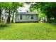 Expansive backyard with a well-manicured lawn, mature trees, and glimpses of neighboring houses at 2966 N Olney St, Indianapolis, IN 46218