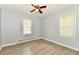 Well-lit bedroom with two windows, wood-look flooring, a ceiling fan, and neutral gray walls at 2966 N Olney St, Indianapolis, IN 46218