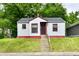 Quaint home with white siding, red trim, concrete steps and iron security door, nestled in greenery at 2966 N Olney St, Indianapolis, IN 46218