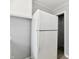 A white refrigerator stands in a kitchen with white cabinets and gray walls at 2966 N Olney St, Indianapolis, IN 46218