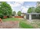 Backyard view featuring a garage, lush lawn, wooden fence, and a gravel area surrounded by mature trees at 31 N Bolton Ave, Indianapolis, IN 46219