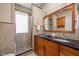 Bathroom featuring a glass shower, double vanity sinks, and stone tile at 31 N Bolton Ave, Indianapolis, IN 46219