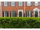 A brick townhome with dark shutters and meticulously trimmed front hedge, offering privacy and charm at 4332 Heyward Pl, Indianapolis, IN 46250