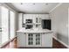 Well-lit kitchen island featuring white cabinetry and a sink creates a functional workspace, complemented by wood floors at 4332 Heyward Pl, Indianapolis, IN 46250