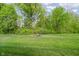 Spacious backyard with green grass and a fire pit featuring a circle of dark mulch at 5020 Eldon Dr, Noblesville, IN 46062