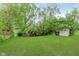 Lush backyard with mature trees, green lawn, and a storage shed at 5083 Emmert Dr, Indianapolis, IN 46221
