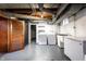 The basement features a washer, dryer, and freezer, with a painted gray floor and exposed duct work overhead at 5428 E 10Th St, Indianapolis, IN 46219