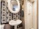 Charming bathroom featuring patterned wallpaper, pedestal sink, and tiled walk-in shower at 5428 E 10Th St, Indianapolis, IN 46219