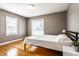 This is a bedroom with wooden floors and two windows, with a neatly made bed and a nightstand on the side at 5428 E 10Th St, Indianapolis, IN 46219