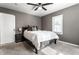 This is a carpeted bedroom featuring a ceiling fan, a door, a window, and a neatly made bed with a nightstand on the side at 5428 E 10Th St, Indianapolis, IN 46219