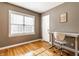 This is a bedroom with wood floors, a window, a closet, and a desk with a chair in the corner at 5428 E 10Th St, Indianapolis, IN 46219