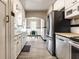 Long view of the galley kitchen featuring stainless steel appliances, white cabinets, and a view to the breakfast nook at 5428 E 10Th St, Indianapolis, IN 46219