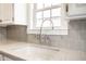 Close-up on the kitchen sink, backsplash, countertop and faucet with a view to the backyard at 5428 E 10Th St, Indianapolis, IN 46219