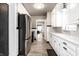 Long kitchen with stainless steel appliances, white cabinets, and a view to the dining room at 5428 E 10Th St, Indianapolis, IN 46219