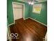 Bedroom featuring green walls, hardwood floors, a window, and a closet with shelving at 5802 Bertha St, Indianapolis, IN 46241