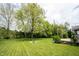 Lush backyard showcasing a well-maintained lawn, mature trees, fire pit, and landscaping at 5824 W Commonview Dr, McCordsville, IN 46055