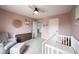 Bedroom with pink walls, gray glider, white crib, and brown dresser at 5824 W Commonview Dr, McCordsville, IN 46055