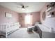 Bedroom with pink walls, white crib, dresser, and gray glider at 5824 W Commonview Dr, McCordsville, IN 46055
