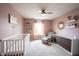 Bedroom with pink walls, white crib, glider, and bookshelves at 5824 W Commonview Dr, McCordsville, IN 46055
