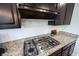 Close-up of kitchen stove and granite countertop featuring dark cabinets and stainless steel appliance at 5824 W Commonview Dr, McCordsville, IN 46055