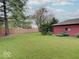 Green backyard featuring a wood fence, complemented by lush lawn and a detached garage, ideal for outdoor activities at 6069 E 15Th St, Indianapolis, IN 46219