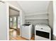 Laundry room with white washer and dryer and storage shelves next to a doorway leading outside at 631 Prospect St, Indianapolis, IN 46203