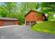 View of the back of the house, featuring multiple garage spaces and mature trees at 6794 E Ann St, Camby, IN 46113