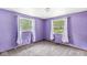 This bedroom has purple walls, carpet, two windows, and white curtains at 7503 Grandview Dr, Indianapolis, IN 46260