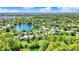 Serene aerial view of homes surrounding a peaceful lake in a lush green community, all under a bright blue sky at 7670 Lippincott Way, Indianapolis, IN 46268