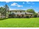 A spacious backyard features a well-manicured lawn and a stone-accented two-story home with an outdoor patio at 781 Dayton Dr, Carmel, IN 46033