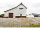 White barn with a garage door and normal door on a gravel lot next to a white house at 7895 E 175 N, Franklin, IN 46131