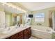Bathroom with double sink vanity, a large mirror, and a separate tub and shower at 9311 Windrift Way, Zionsville, IN 46077