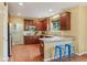 Well-lit kitchen featuring rich wood cabinets, neutral countertops, and a breakfast bar with two blue stools at 9311 Windrift Way, Zionsville, IN 46077