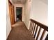 Upstairs hallway featuring carpet flooring with multiple doors and a wooden railing at 1026 Summer Way Dr, Shelbyville, IN 46176