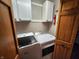 Efficient laundry room with modern, front-loading washer and dryer beneath white cabinets and next to a wooden door at 1026 Summer Way Dr, Shelbyville, IN 46176
