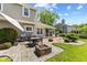 Serene backyard with stone patio, dining set, fire pit, and lush landscaping, ideal for outdoor entertaining at 10988 Eaton Ct, Fishers, IN 46038