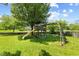 Well-kept backyard with a wooden playset beneath a mature shade tree, offering endless outdoor fun at 10988 Eaton Ct, Fishers, IN 46038