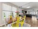 Sunlit dining area featuring a rustic wood table, vibrant yellow chairs, and an open view to the modern kitchen at 10988 Eaton Ct, Fishers, IN 46038