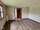 Large living room with new wood-look flooring, fresh paint, and a view of the door to the hall at 1103 Canal St, Anderson, IN 46012