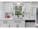 Kitchen sink with white cabinets, black faucet, subway tile backsplash, and view of the outdoors at 1829 Kessler Blvd W Dr, Indianapolis, IN 46228