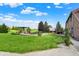 Expansive backyard features a patio, lush lawn, beautiful landscaping, and mature trees under a bright blue sky at 186 W 600 N, Alexandria, IN 46001