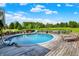 A backyard pool surrounded by a wooden deck with chairs, lush grass, and a treeline at 186 W 600 N, Alexandria, IN 46001