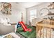 Bright Bedroom featuring a crib, dresser, glider, fun decor, and a whimsical slide at 3047 N New Jersey St, Indianapolis, IN 46205